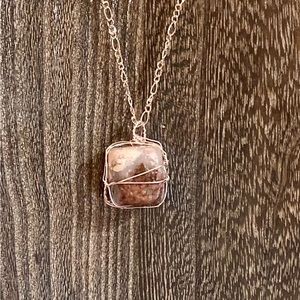 Wire-wrapped Rhodonite tumbled, smooth stone pendant on rose gold necklace.